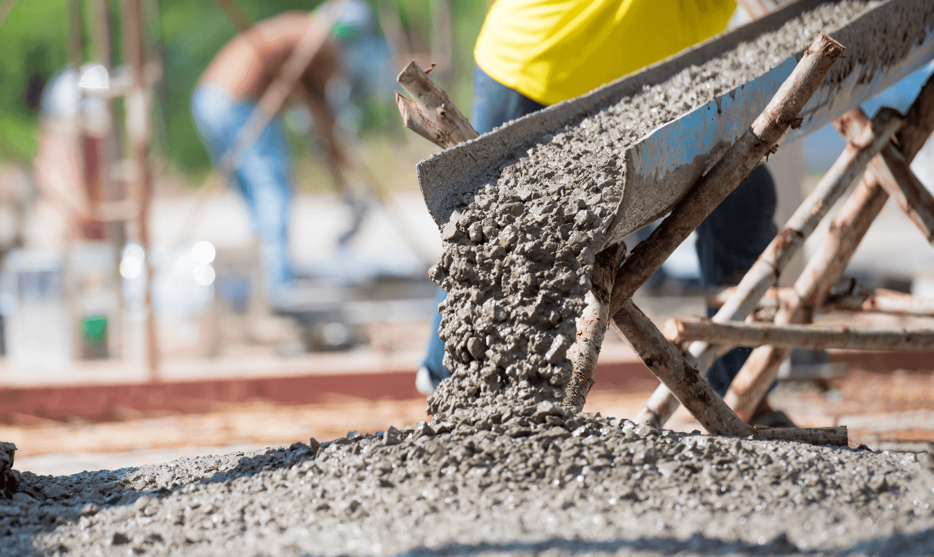 Concrete being poured from a chute on a construction site.